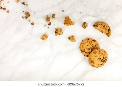 Chocolate chips cookies and crumbs, shot from above on a white marble background, with a place for text - Powered by Shutterstock