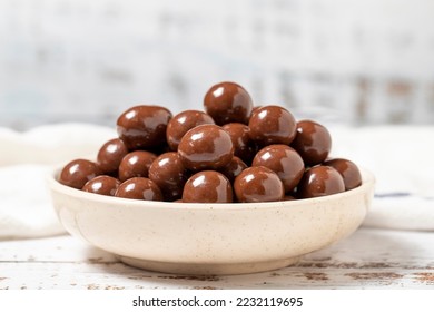 Chocolate coated hazelnut dragee. Hazelnut dragee chocolates on a white wood background. close up