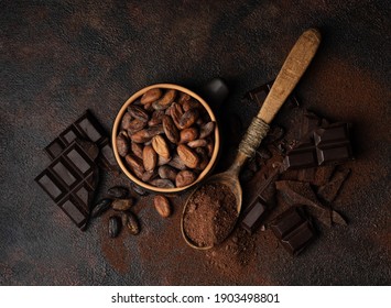 Chocolate and cocoa concept. Cocoa powder in a spoon near cocoa beans and broken chocolate on a black background