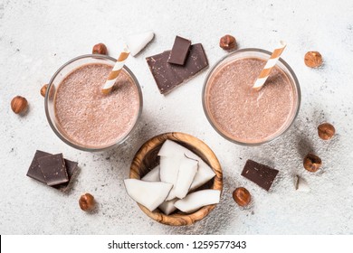 Chocolate coconut hazelnut milkshake or smoothie in two glasses on white table. Top view.