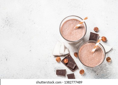 Chocolate coconut hazelnut milkshake or smoothie in two glasses on white table. Top view with copy space.