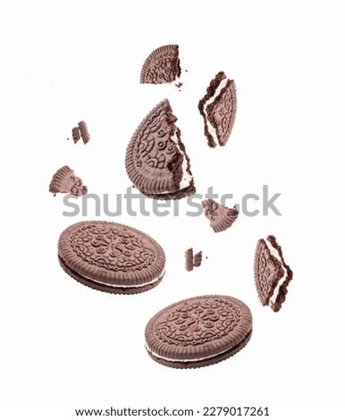 Chocolate cookies or biscuits, with  vanilla cream filling, falling on white background