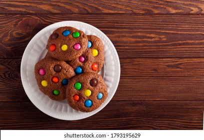 Chocolate cookies with colorful candies on plate