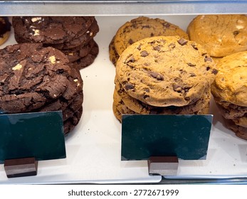 Chocolate cookies stack and bakery biscuits in showcase. Sweet snack, dessert selection, sugar intake, baked goods display, and confectionery assortment in cafe environment.