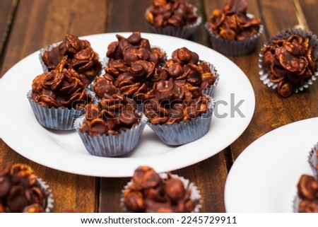 Chocolate cornflake cookies served on white plates. Chocolate cornflake cake in blue paper cupcake case