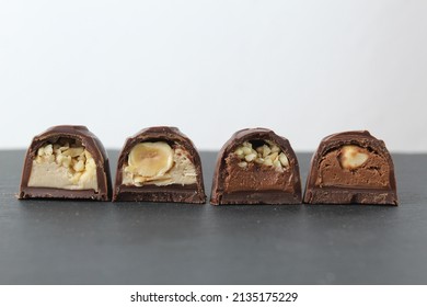chocolate corus candies in section with a white chocolate filling with hazelnuts peanuts praline ganache on a gray background with space for text and copyspace. Day chocolate sweets without diet.