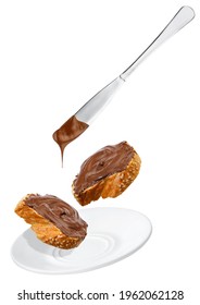 chocolate cream falling from knife on baguette in saucer isolated on white background