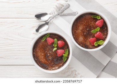 Chocolate creme brulee dessert consisting of a rich custard base topped with a layer of hardened caramelized sugar close-up in a ramekin on the table. Horizontal top view from above