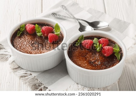 Chocolate creme brulee dessert consisting of a rich custard base topped with a layer of hardened caramelized sugar close-up in a ramekin on the table. Horizontal
