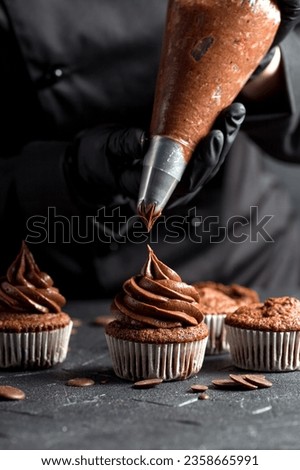 Chocolate cupcakes. The confectioner decorates the cupcake with cream using a pastry bag. Homemade baking concept. Soft focus
