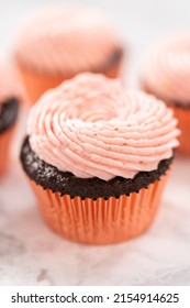 Chocolate cupcakes frosted with strawberry buttercream frosting.
