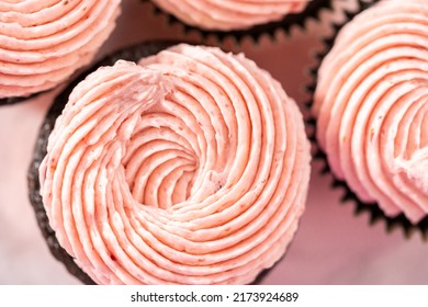 Chocolate cupcakes frosted with strawberry buttercream frosting.