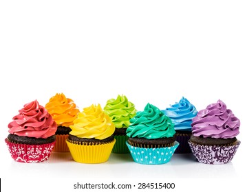 Chocolate cupcakes in rows with colorful icing on a white background.
