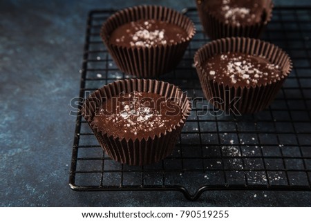 chocolate cups with salted caramel and nuts, dark blue background, selective focus