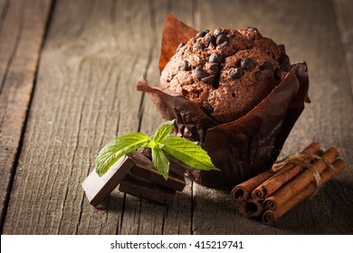 chocolate dark cooked muffin with mint on a wooden table with cinnamon, anise, chocolate.