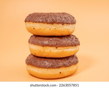 Chocolate donut with chocolate chips on an orange background. close-up.