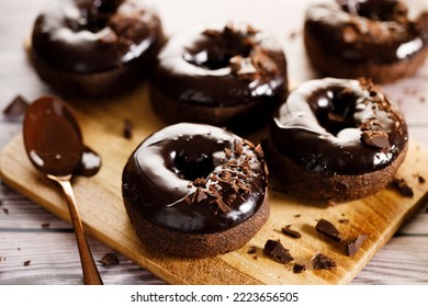 Chocolate donuts with chocolate pieces topping on wooden table background.