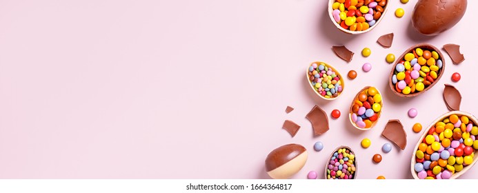 Chocolate Easter Border With Chocolate Eggs And Colorful Candy Sweets On Pastel Pink, Copy Space. Traditional Easter Treats Flat Lay, Holiday Background, Web Poster