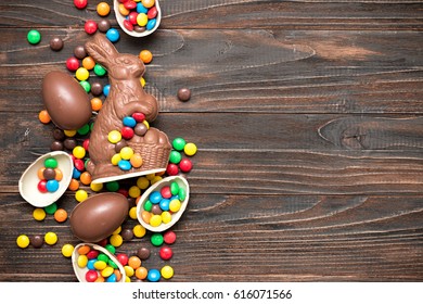 Chocolate Easter bunny with chocolate eggs and colorful dragees on the wooden background. - Shutterstock ID 616071566