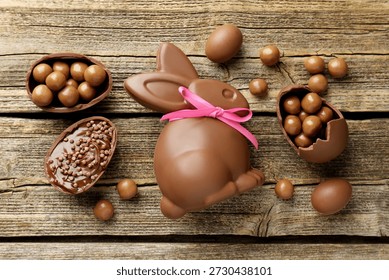 Chocolate Easter bunny and eggs on wooden table, flat lay