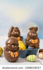 Chocolate Easter chicken in the shell and hares with eggs on a light background.