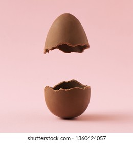 Oeuf de Pâques au chocolat cassé en deux sur fond rose pastel avec espace pour copie créative. Concept minimaliste de vacances de Pâques.