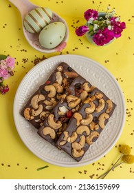 Chocolate Easter egg dessert topped with nuts on yellow background, top view, yellow background, flat lay