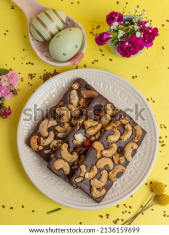 Chocolate Easter egg dessert topped with nuts on yellow background, top view, yellow background, flat lay