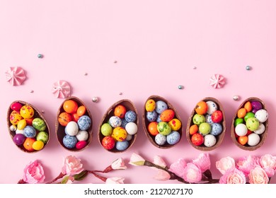 Chocolate easter eggs and decor flat lay for kids easter hunt egg concept on pink background. Sweets in the shape of an egg.