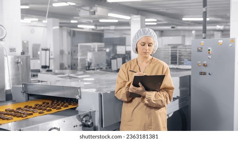 Chocolate factory worker inspecting production line conveyor with sweets candy. Concept food industry banner. - Powered by Shutterstock