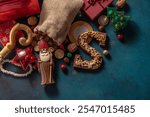 Chocolate figurine of St. Nicholas with gifts on blue background. Holiday background Saint Nicholas, Sinterklaas, gifts for children with cookies, chocolate, nuts and sweets