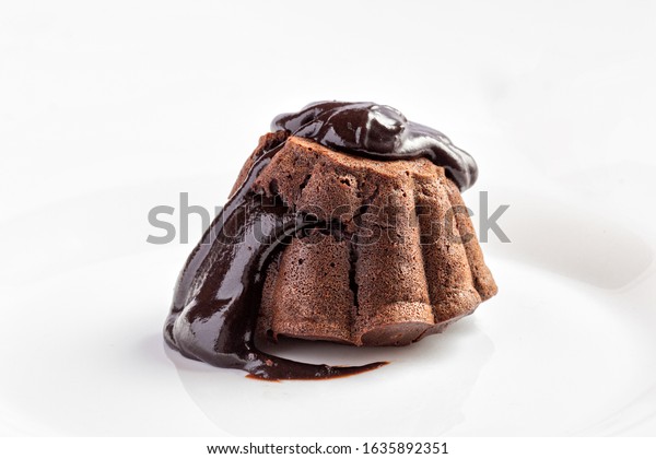 Chocolate fondant cake with flowing chocolate on white\
plate close up