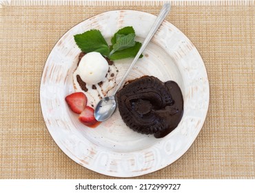 Chocolate Fondant Cake In The Shape Of A Broken Heart With Ice Cream, Strawberries, Mint On A White Served Table.