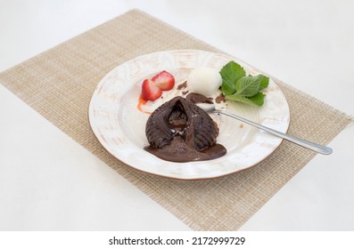 Chocolate Fondant Cake In The Shape Of A Broken Heart With Ice Cream, Strawberries, Mint On A White Served Table.