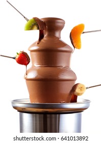 Chocolate Fondue Fountain With Fresh Tropical Fruit On Forks Being Dipped In The Rich Creamy Sauce In A Side View Isolated Over White