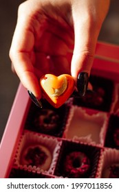 Chocolate And Fruit Candies In A Pink Box In The Girl's Hand