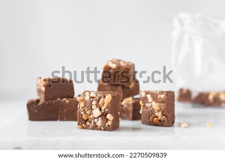 chocolate fudge with nuts on a marble tray, chocolate fudge cut into pieces, fudge candy on a marble tray