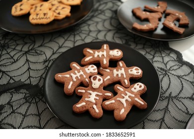 Chocolate Halloween sweets cookies handmade and baked in skeleton shaped with textile cobweb on the background. 