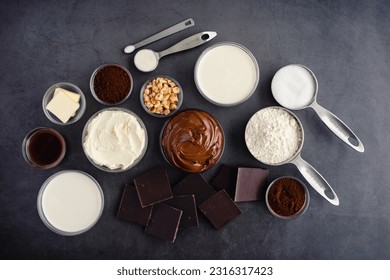 Chocolate Hazelnut Mousse Cake Ingredients on a Dark Background: Hazelnut spread, dark chocolate, cream, and other cake ingredients