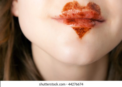 chocolate heart on lips of pretty young woman - clouseup