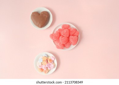 Chocolate heart, pink candies and colorful heart candy on a plate in a pink background  - Powered by Shutterstock
