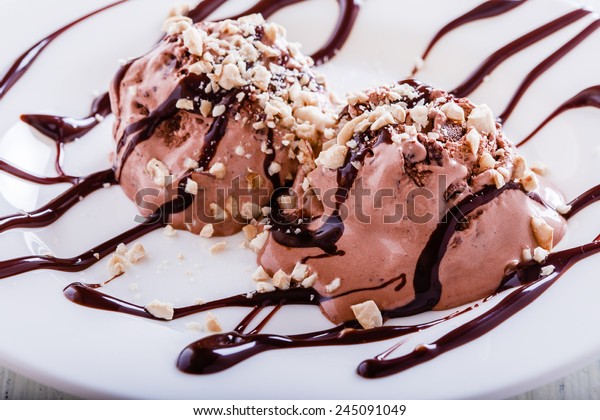 Chocolate ice cream with cashews and chocolate
syrup on white table