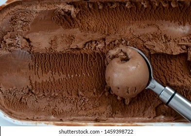 Chocolate Ice Cream In A Container With A Scoop