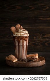 Chocolate Ice cream milkshake milkshake in a tall glass with whipped cream, savoiardi cookies and cocoa
