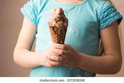 Chocolate ice cream in a waffle horn in the hands of a child. Selective focus. Front view. - Shutterstock ID 1072038248