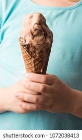  Chocolate ice cream in a waffle horn in the hands of a child. Selective focus. Front view.  - Shutterstock ID 1072038413