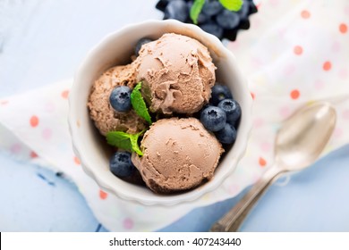 Chocolate ice-cream with mint and fresh berries on rustic wooden bllue background, top view