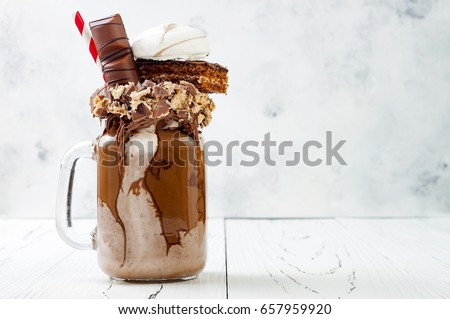 Chocolate indulgent extreme milkshake with brownie cake, marshmallow and sweets. Crazy freakshake food trend. Copy space