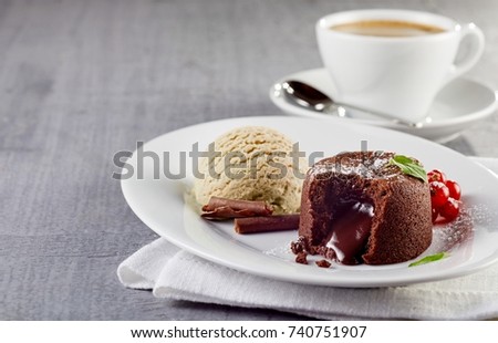 Chocolate lava cake with ice cream served on plate against cup of coffee