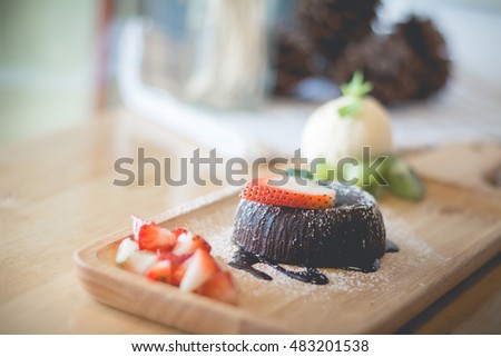 chocolate lava cake with vanilla ice cream and strawberry. chocolate lava on wood plate. Hot chocolate pudding with fondant centre.(vintage, selective focus)